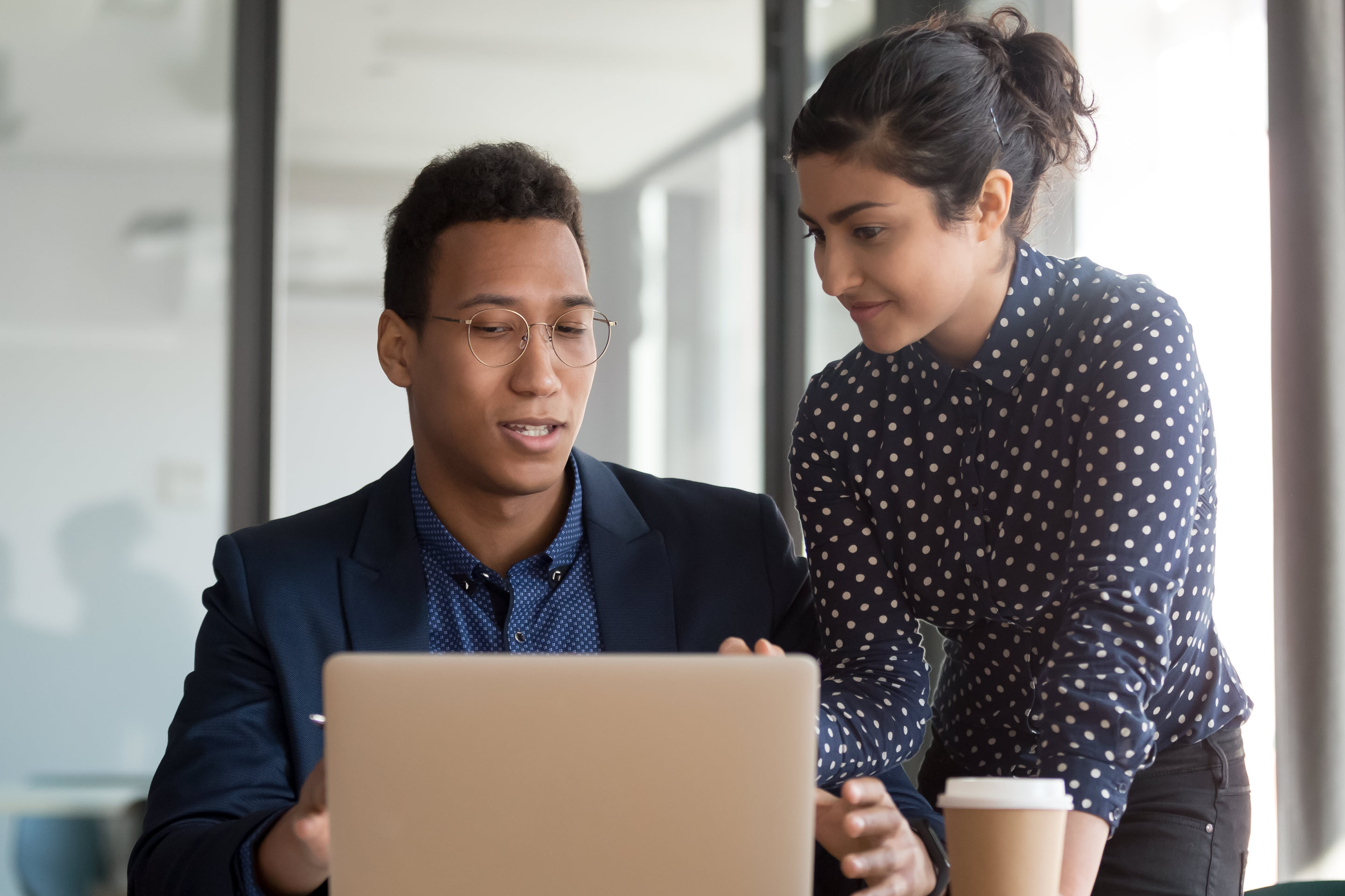 A tax technology professional assists another, using his laptop, in order to implement a seamless ERP upgrade.