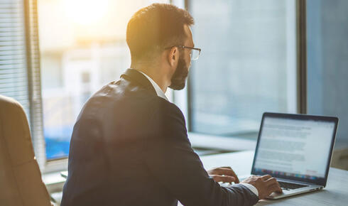 Man sitting at office desk and typing on laptop