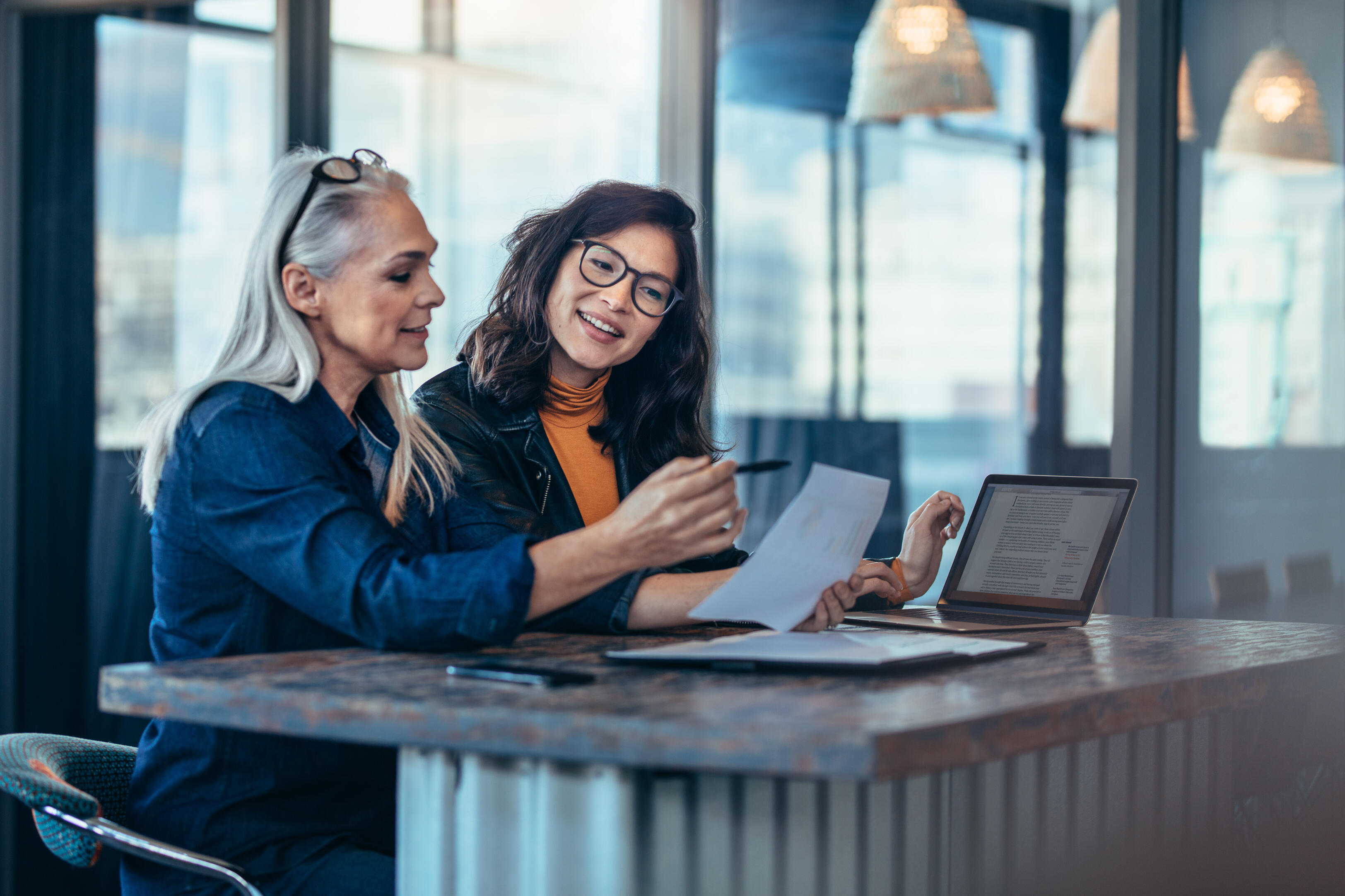 Women colleagues looking at computer and papers