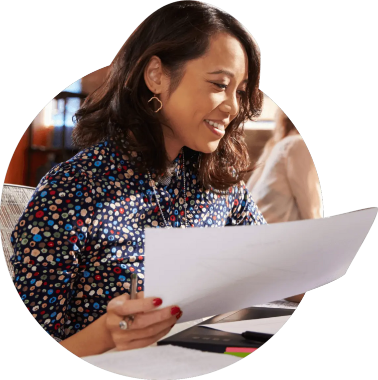 Woman holding business documents over a laptop.