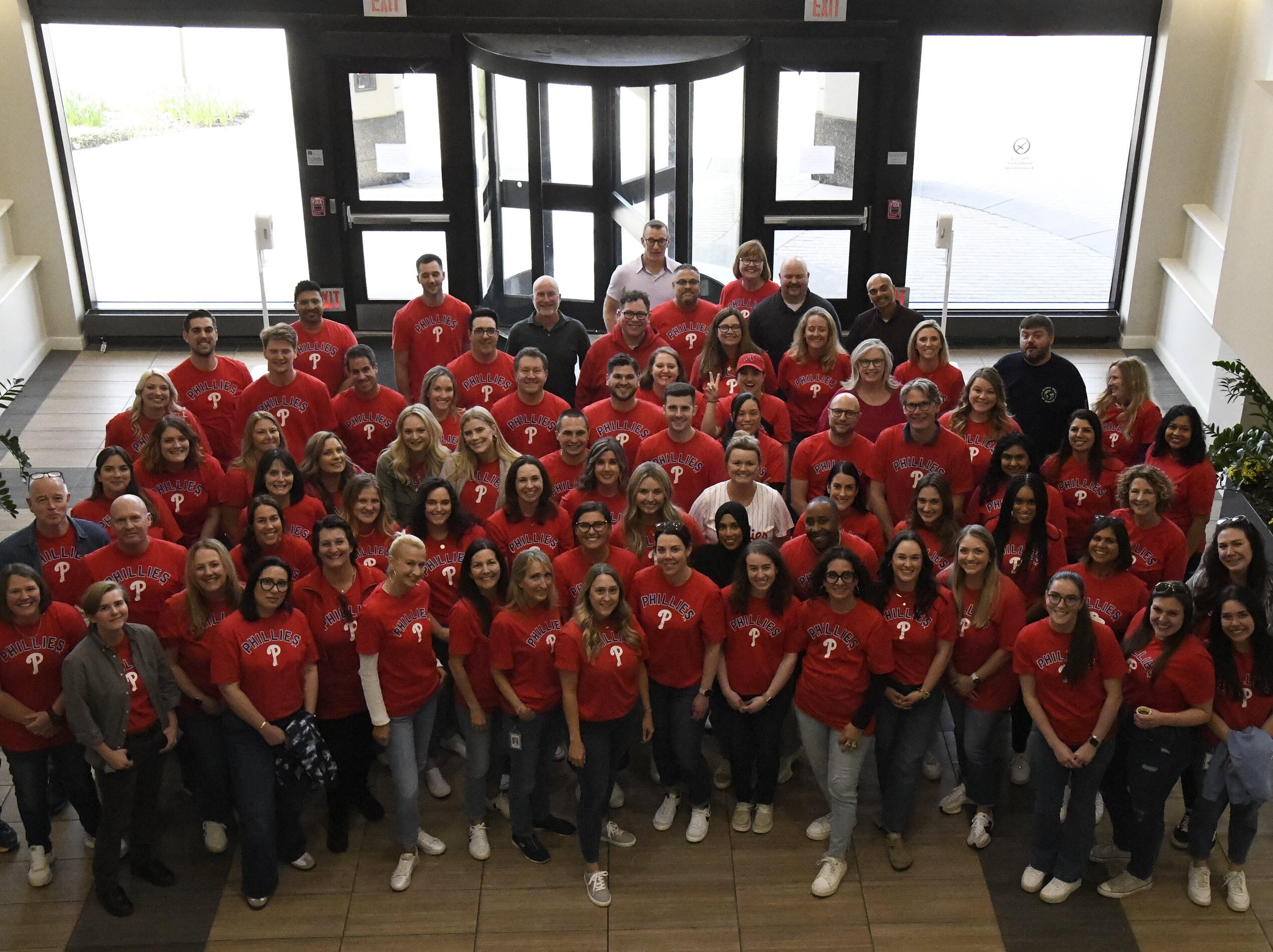 Vertex employees gather in the lobby of our King of Prussia office to take a group photo, with everyone wearing a Philly's shirt to celebrate a team outing to the game.